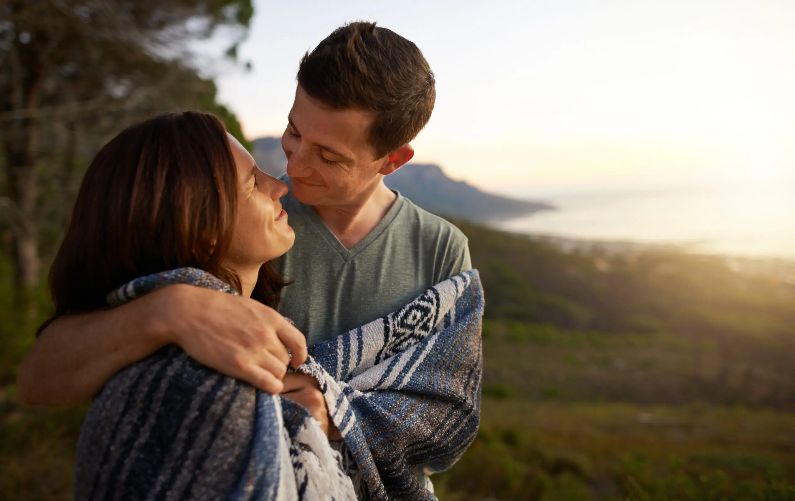 Shot of a young couple wrapped together in a blanket